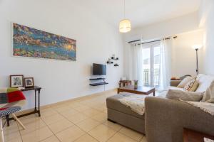 a living room with a couch and a tv at Spacious seaview apartment in Heraklion in Heraklio