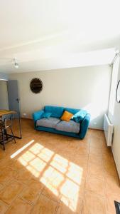 ein Wohnzimmer mit einem blauen Sofa und einem Tisch in der Unterkunft Maison de plain-pied avec un grand jardin in Malicorne-sur-Sarthe