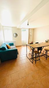 ein Wohnzimmer mit einem blauen Sofa und einem Tisch in der Unterkunft Maison de plain-pied avec un grand jardin in Malicorne-sur-Sarthe