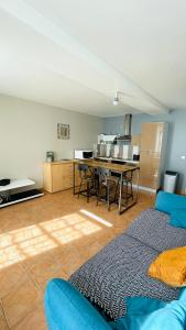 ein Wohnzimmer mit einer blauen Couch und einer Küche in der Unterkunft Maison de plain-pied avec un grand jardin in Malicorne-sur-Sarthe