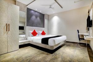 a bedroom with a large bed with red pillows at Capital O Abri Krishna in Indore