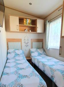 2 Betten in einem kleinen Zimmer in einem Wohnwagen in der Unterkunft Luke's Hideaway at Seal Bay Resort in Selsey