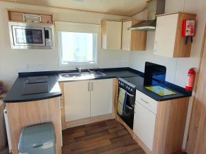 eine kleine Küche mit Spüle und Herd in der Unterkunft Luke's Hideaway at Seal Bay Resort in Selsey
