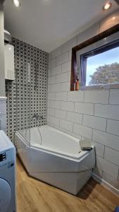 a white bath tub in a bathroom with a window at Apartament Classic in Malbork +27 photos