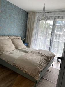 a bed in a bedroom with a large window at Apartament SZAFIROWY SEN z widokiem na morze in Pogorzelica