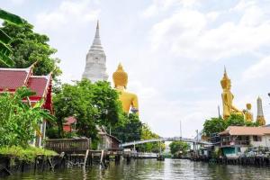 une rivière avec un groupe de bâtiments et un temple dans l'établissement Longtail Boat Tour bangkok Tour Klong, à Chinatown