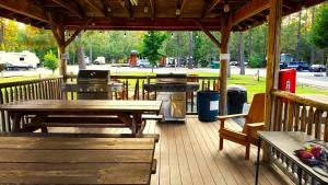 a wooden deck with picnic tables and a grill at Gold Creek Cabin 3 - Sleeps up to 4 in O'Brien