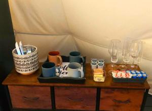 a wooden table with cups and glasses on it at Wild Horses Luxury Tipi - Adjustable King Bed in O'Brien