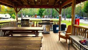 a wooden deck with picnic tables and a grill at Wild Horses Luxury Tipi - Adjustable King Bed in O'Brien