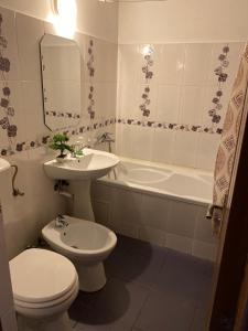 a bathroom with a toilet and a sink and a tub at Eva Apartments Mall 90mp in Bacău