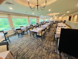 a dining room with white tables and chairs and windows at Town & Country Inn & Resort in Gorham