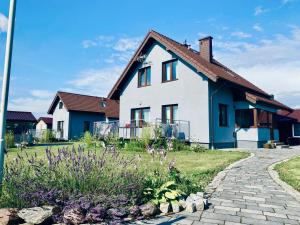a white and blue house with a brick driveway at Dom Wczasowy u Marci in Tymień