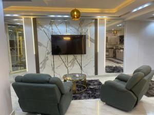 ein Wohnzimmer mit zwei Stühlen und einem Fernseher in der Unterkunft شقة فندقية غرفتين بكمبوند قرب ميدان جهينة in Sheikh Zayed