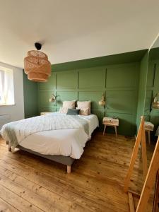 a bedroom with a large bed with a green wall at La Grange d'Annalys in Granges-Narboz