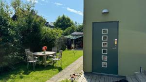 a patio with a table and chairs and a green door at Unikt boende i egen del av hus nära stad och strand in Ystad