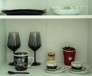 a shelf with two wine glasses and cups on a table at M & M Studio in Jurilovca