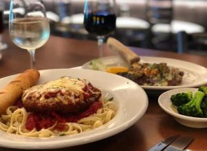 a table with plates of pasta and meatballs and a glass of wine at Town & Country Inn & Resort in Gorham