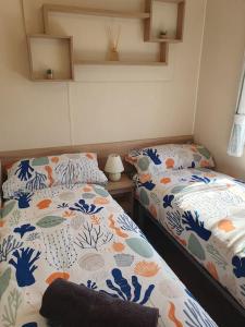 a bedroom with two beds with blue and white covers at Billing Aquadrome - Alberta Caravan 2 Bedroom Sleep 6 in Northampton