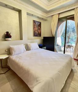un grande letto bianco in una stanza con una finestra di Palmeraie 5 Vue Piscine et Jardin a Marrakech