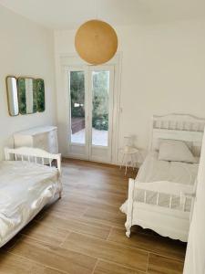 een witte slaapkamer met 2 bedden en een groot raam bij Villa des 3 Ponts, Piscine au calme in Nîmes