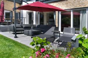 patio z kanapą i czerwonym parasolem w obiekcie Villa Mama - Luxus und Lebensfreude w mieście Seefeld in Tirol