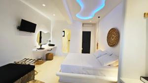 米克诺斯城ELLI TROPiCAL LUXURY SUITES SUNSET-INFINITY POOL- SEA SIDE-NEAR CENTER PARKING的一间带床和电视的白色卧室
