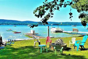 un gruppo di sedie seduti sull'erba vicino all'acqua di Birch Shores Resort - The Hemlock Cottage a Empire