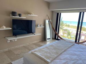 a bedroom with a tv and a bed with a view at Exclusivo departamento frente al Mar en Kinuh in Telchac Puerto