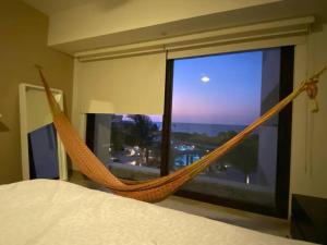 a hammock in front of a window in a bedroom at Exclusivo departamento frente al Mar en Kinuh in Telchac Puerto +24 photos
