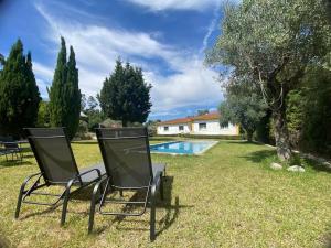 two chairs sitting in the grass near a swimming pool at Quinta O Cabecinho in Torres Novas