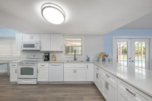 a white kitchen with white cabinets and a sink at Gorgeous Ranch Style Pool Home on One Acre Lot in Fort Myers