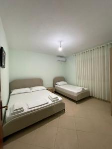 a bedroom with two beds and a window at Drilon Apartment in Sarandë