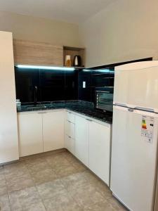 a kitchen with white cabinets and a white refrigerator at Hospedaje Los Lapachos in Libertador San Martín