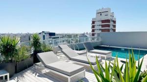un balcon avec des chaises et une piscine dans un immeuble dans l'établissement Lujoso Penthouse a estrenar en Sofisticado Barrio y Edificio Vista panorámica 100m2 Gimnasio Piscina Lujoso Salon de Fiestas Parking privado con acceso directo al departamento, à Buenos Aires
