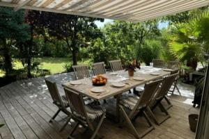 a wooden table and chairs on a patio at holiday home with indoor pool, Le Porge in Le Porge