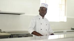 a man in a chefs hat standing in a kitchen at The Grand Palace Hotel in Singine