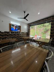 BarkotHotel Rest and Bite的用餐室配有大木桌和平面电视。