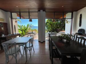 a dining room with tables and chairs and a large window at Pousada Tagomago in Abraão