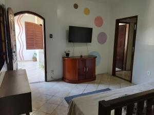 a living room with a tv on a wall at Sea Like in Arraial do Cabo