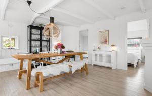 a white dining room with a table and a bench at Three-Bedroom Holiday Home In Otterup in Otterup