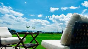 two glasses of wine on a table next to a chair at Farm To Table NORICHIE 1日1組限定の一棟貸し 田園風景と星空を楽しむ 自家農園&地元食材の夕朝食付き in Senboku
