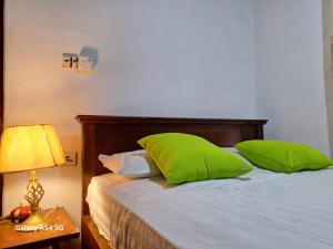 a bedroom with a bed with green pillows and a lamp at Ajanee HomeStay in Tangalle