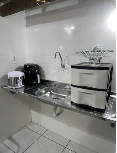 a kitchen counter with a sink and a microwave at Suíte com entrada independente in Ubajara