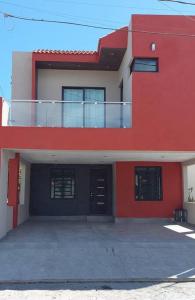 a red building with a balcony on top of it at Casa Vacacional Amaia in Mazatlán