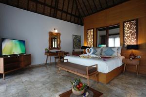 a bedroom with a bed and a flat screen tv at A Villa Gili Air in Gili Air