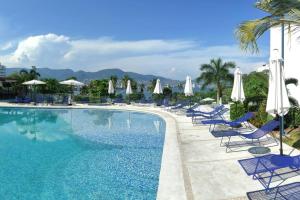 una piscina con sedie e ombrelloni blu di Hermoso Depto en Condominio Astoria ad Acapulco