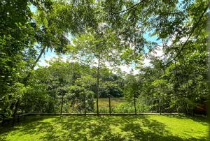 a fence in a field with trees and grass at Cottage by the Lake in Talawatugoda