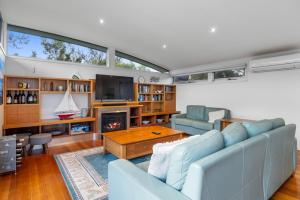 Una sala de estar con un sofá azul y una chimenea. en Sandcastle Haven, en Inverloch