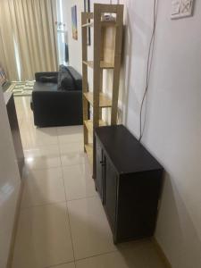 a living room with a black couch and a wooden shelf at Vista Alam Roomstay Homestay in Shah Alam