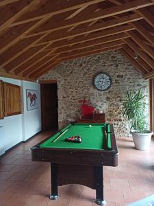 Una mesa de billar en una sala de estar con un reloj. en Maison de charme dans un cadre exceptionnel, en Blennes